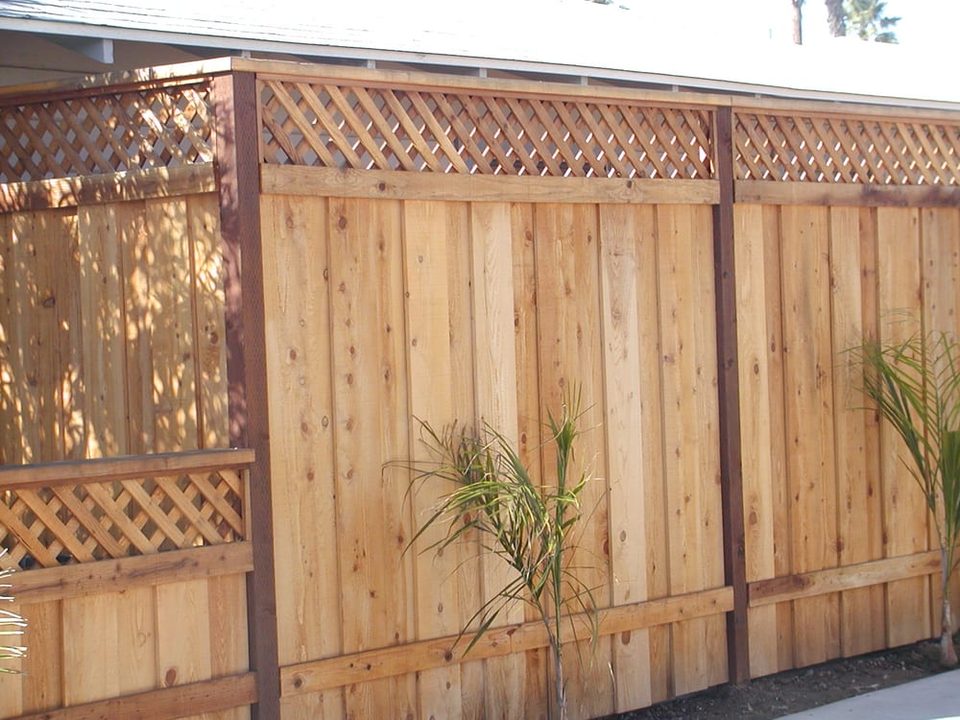 Wood privacy fence with lattice top panels along a long property line